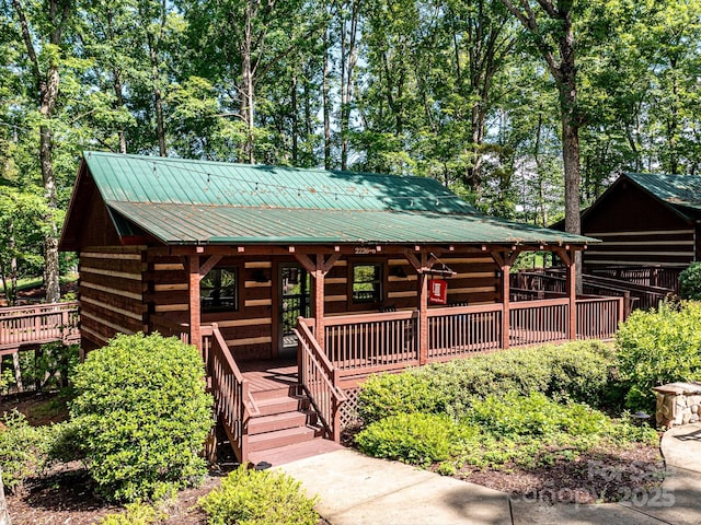 cabin with metal roof, covered porch, and log siding