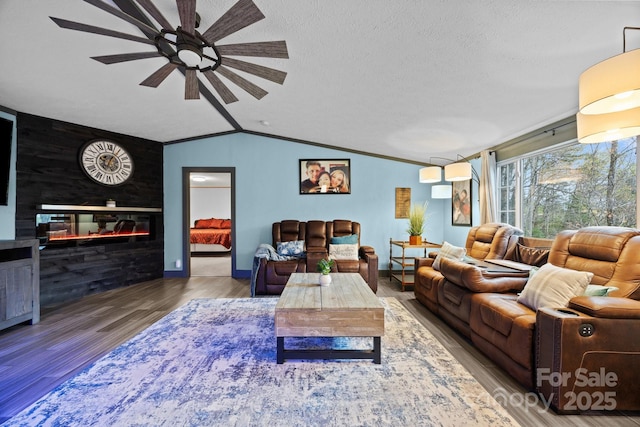 living room featuring a textured ceiling, a glass covered fireplace, a ceiling fan, vaulted ceiling, and wood finished floors