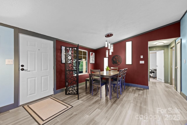 dining room with crown molding, light wood-style flooring, and baseboards