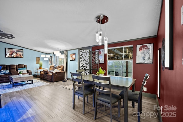 dining area featuring baseboards, wood finished floors, and lofted ceiling