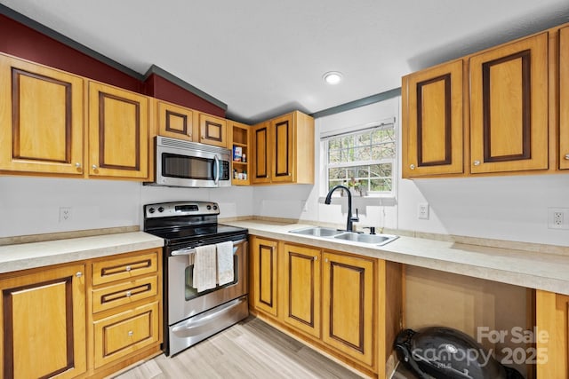 kitchen with a sink, light countertops, light wood-type flooring, vaulted ceiling, and stainless steel appliances