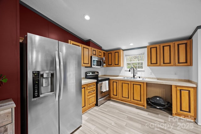 kitchen featuring appliances with stainless steel finishes, light countertops, brown cabinets, lofted ceiling, and a sink