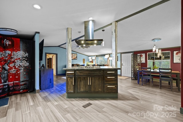 kitchen with ceiling fan, dark brown cabinetry, stainless steel gas stovetop, island range hood, and lofted ceiling
