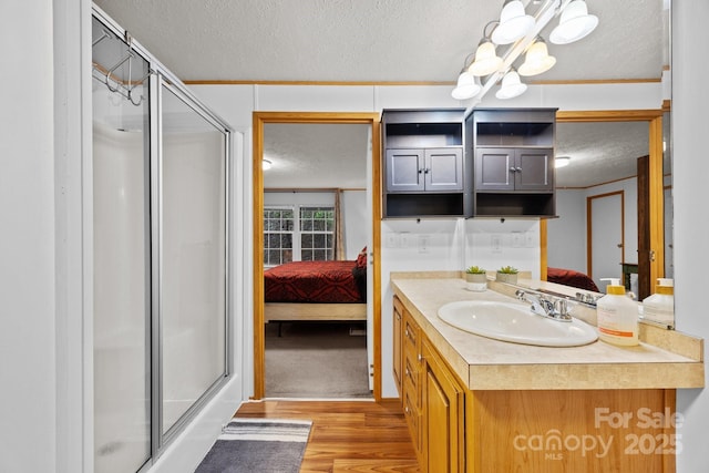 bathroom with ensuite bathroom, a textured ceiling, a shower stall, vanity, and wood finished floors