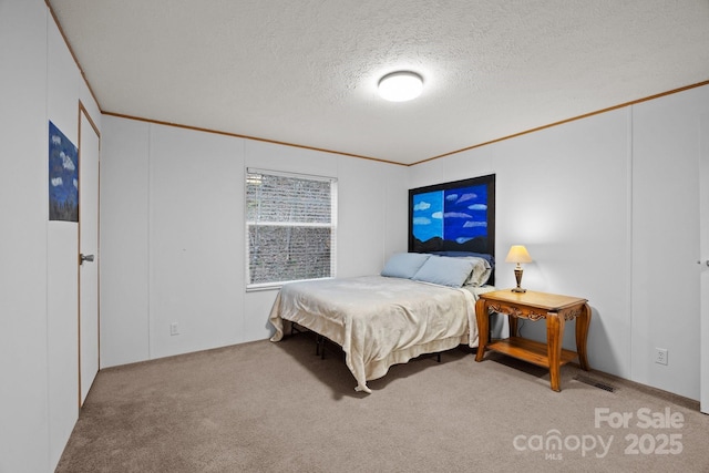 carpeted bedroom featuring ornamental molding and a textured ceiling