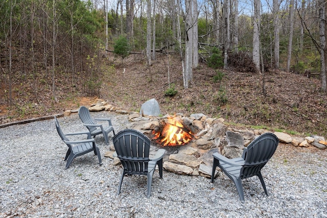 view of yard featuring an outdoor fire pit, a patio, and a forest view