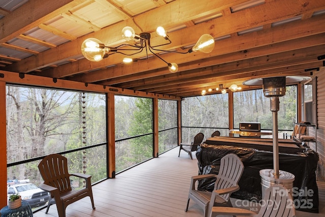 sunroom with wood-type flooring, plenty of natural light, and an inviting chandelier