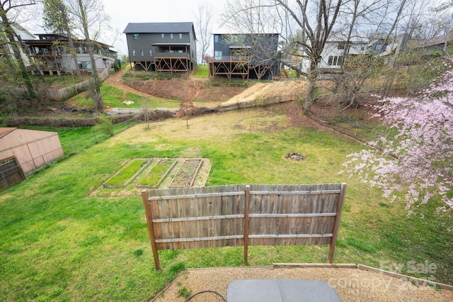 view of yard featuring fence, a vegetable garden, and a deck