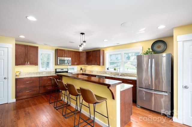 kitchen with a breakfast bar area, appliances with stainless steel finishes, a sink, and plenty of natural light