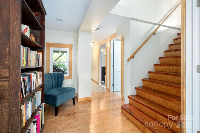 living area featuring baseboards, visible vents, light wood-style floors, and stairs