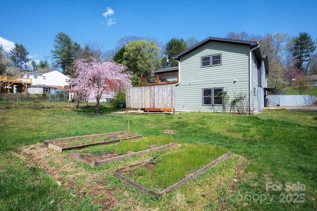 rear view of house with a lawn, a vegetable garden, and a deck