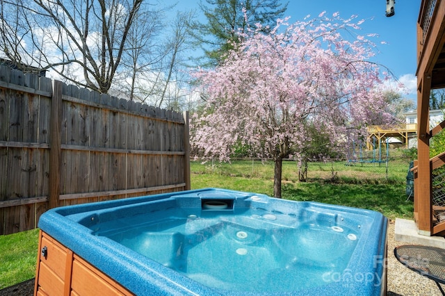 view of swimming pool featuring a hot tub and fence