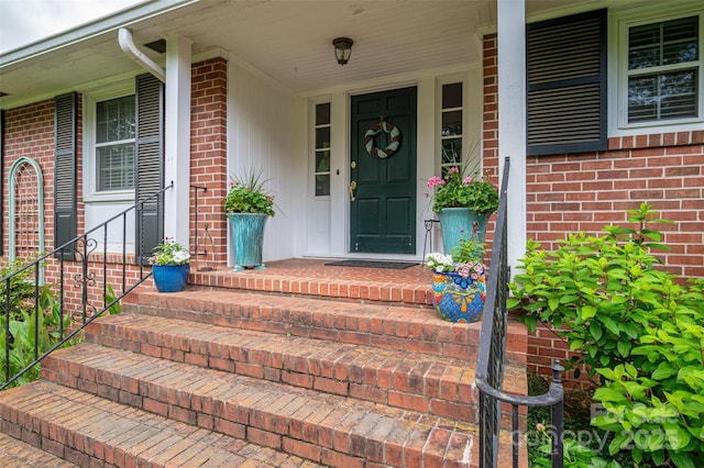 property entrance with covered porch and brick siding