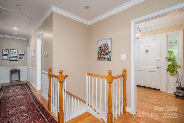 corridor with attic access, crown molding, an upstairs landing, and light wood-type flooring