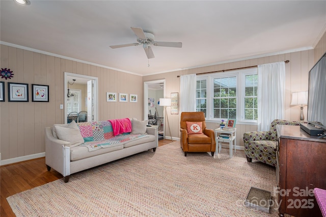 living room featuring baseboards, wood finished floors, ceiling fan, and crown molding