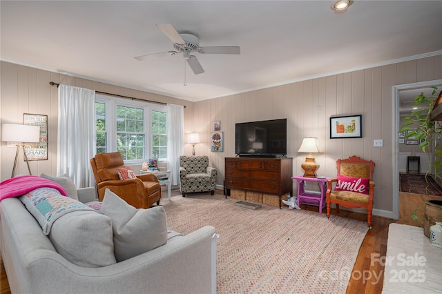 living area featuring wood finished floors, ceiling fan, and ornamental molding