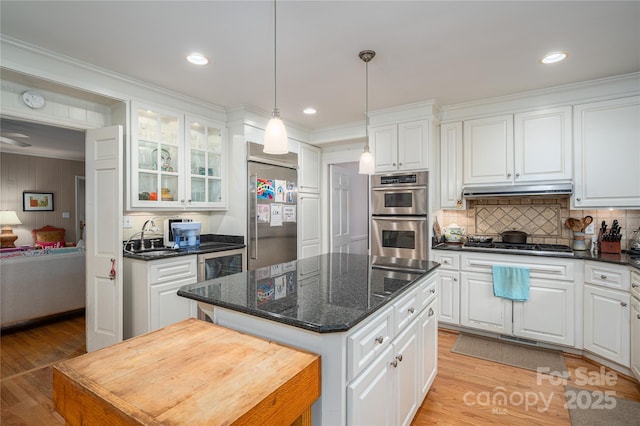 kitchen featuring under cabinet range hood, appliances with stainless steel finishes, white cabinets, a sink, and a center island