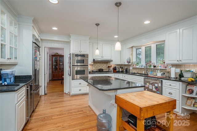 kitchen with light wood finished floors, stainless steel appliances, white cabinets, and a sink
