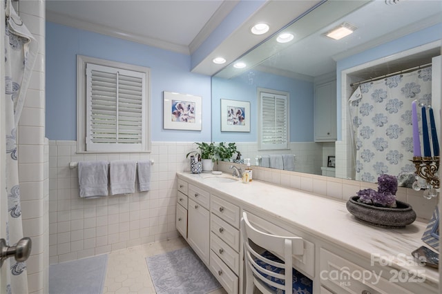 bathroom featuring vanity, crown molding, a wainscoted wall, and tile walls