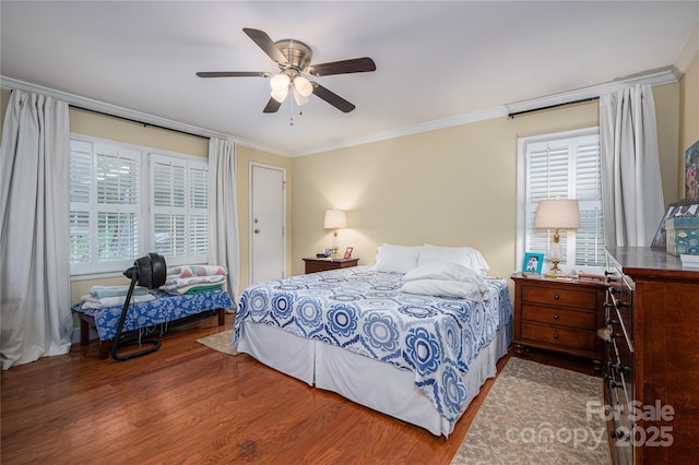 bedroom with wood finished floors, ornamental molding, and multiple windows