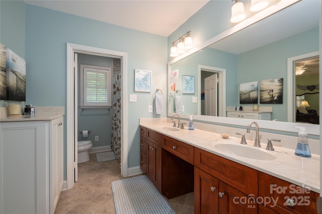 bathroom featuring double vanity, toilet, and a sink