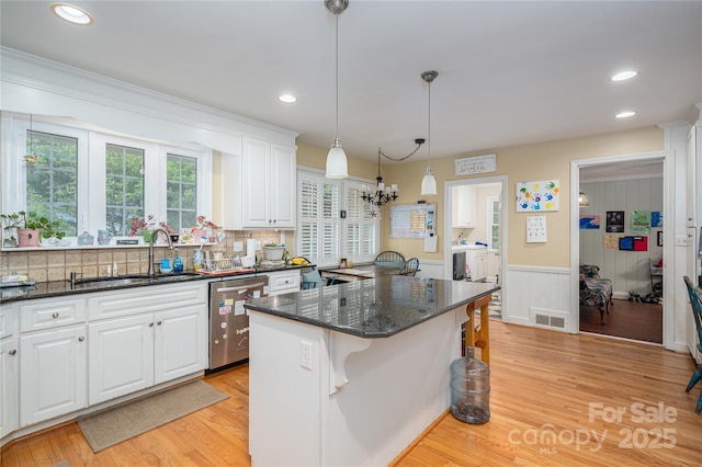 kitchen with a sink, a kitchen bar, a kitchen island, dishwasher, and white cabinets