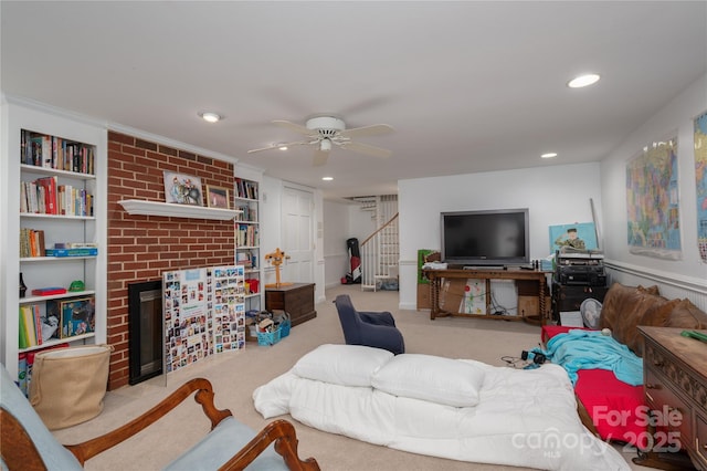 living area with stairway, a ceiling fan, a brick fireplace, and recessed lighting