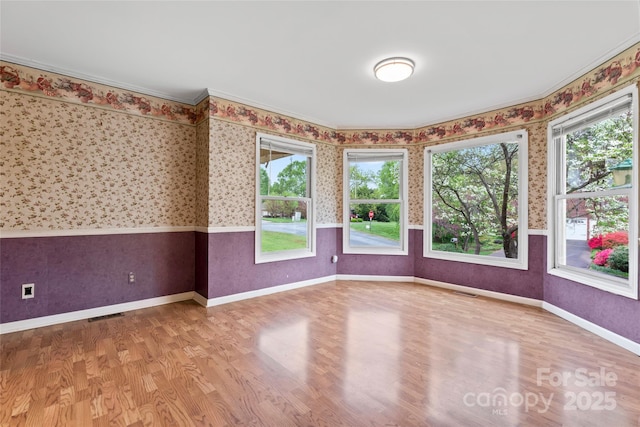 unfurnished room featuring wallpapered walls, wood finished floors, baseboards, and visible vents