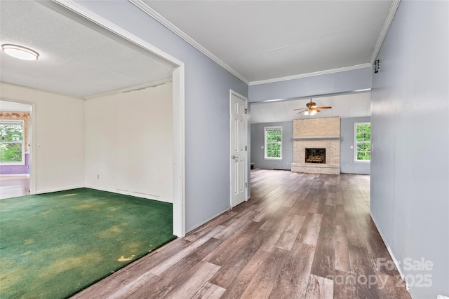 unfurnished living room featuring ornamental molding, plenty of natural light, and a brick fireplace