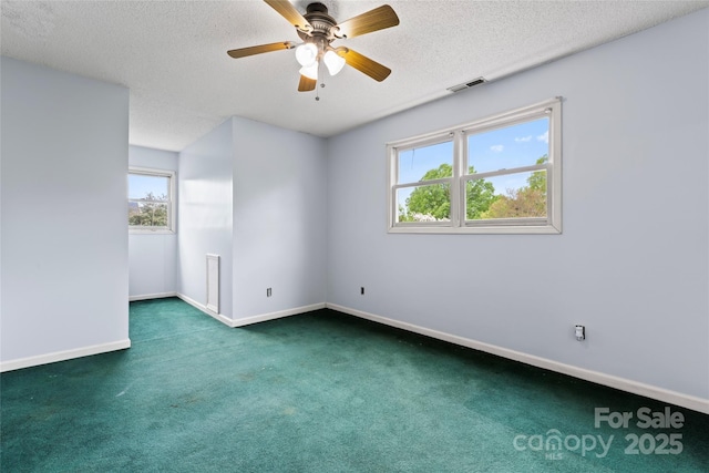 unfurnished room featuring ceiling fan, a textured ceiling, visible vents, dark colored carpet, and baseboards
