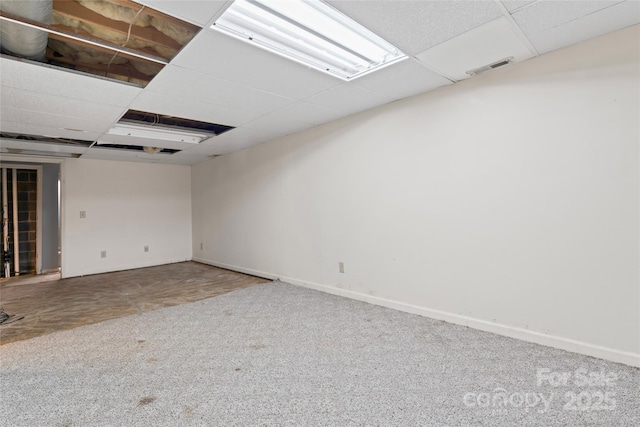 empty room with carpet floors, baseboards, a drop ceiling, and visible vents