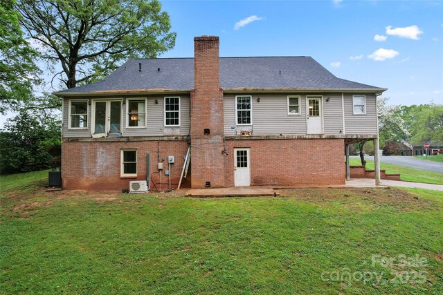 back of house with a chimney, brick siding, a patio area, and a lawn
