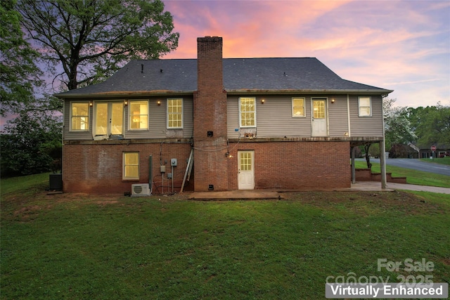 rear view of property featuring a yard, brick siding, a patio area, and a chimney