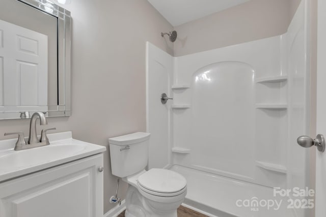 bathroom featuring toilet, a shower, and vanity