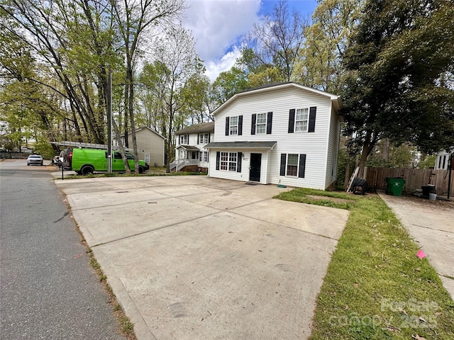 view of front facade with concrete driveway and fence