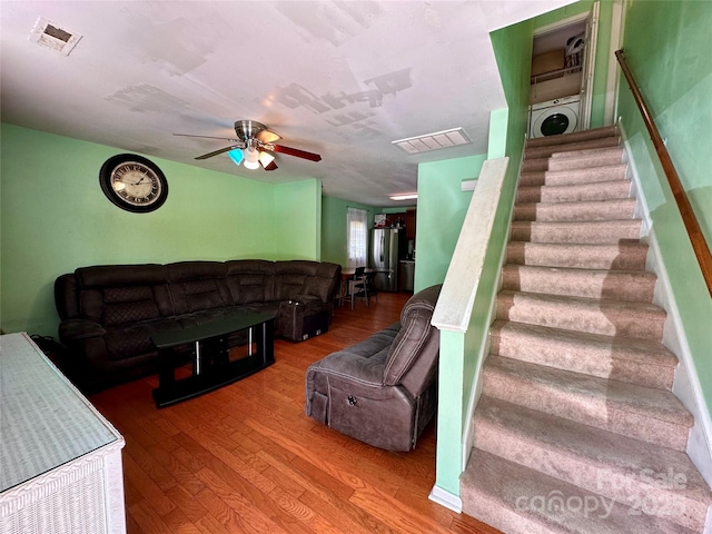 living area with stairway, a ceiling fan, washer / dryer, visible vents, and wood finished floors