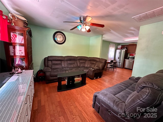 living area featuring visible vents, a ceiling fan, and wood finished floors