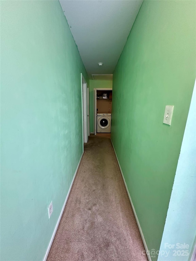 hallway featuring baseboards, washer / dryer, and carpet