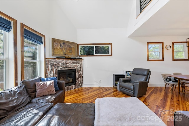 living room with a wealth of natural light, high vaulted ceiling, and wood finished floors