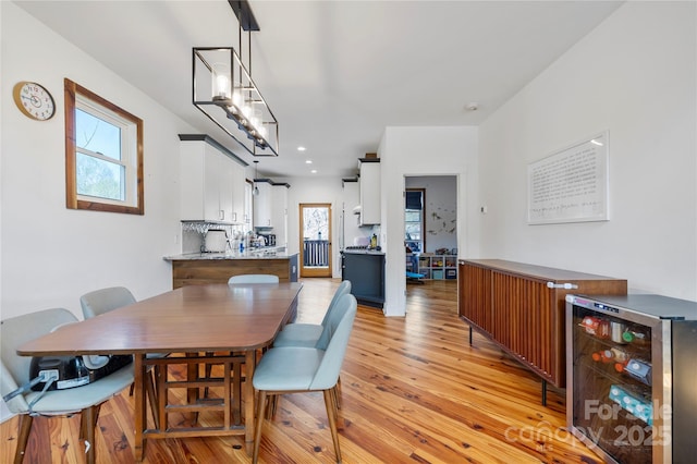 dining room with light wood-type flooring, beverage cooler, and recessed lighting