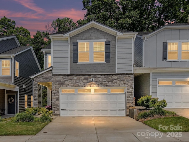 view of front facade featuring stone siding, an attached garage, and concrete driveway