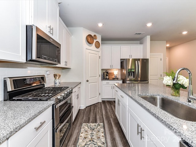 kitchen featuring stainless steel appliances, a sink, white cabinets, dark wood-style flooring, and recessed lighting