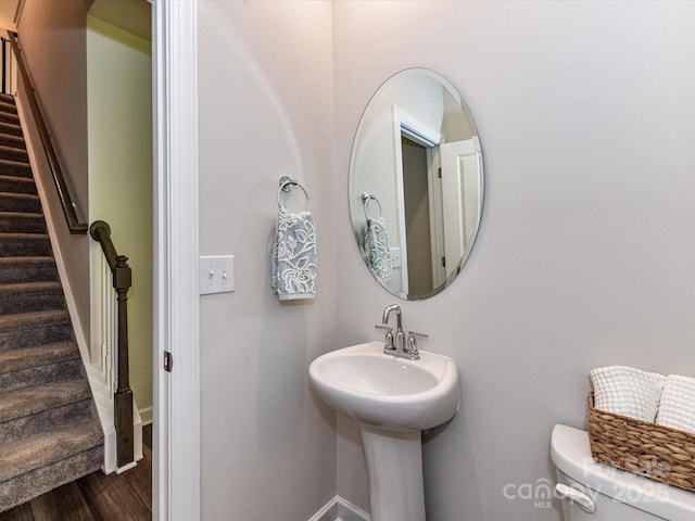 bathroom with wood finished floors, baseboards, toilet, and a sink