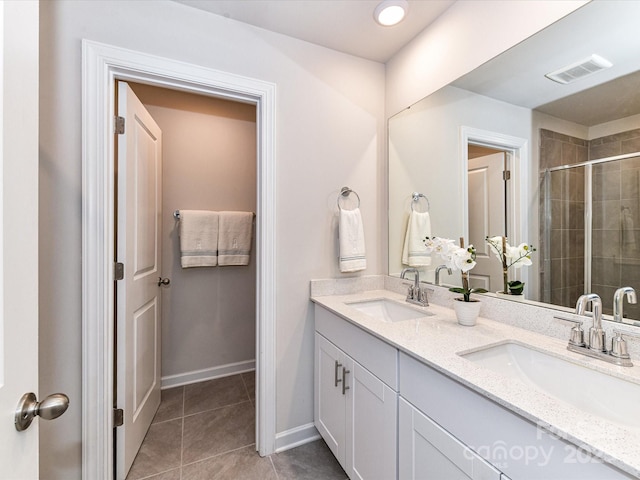 bathroom featuring a stall shower, tile patterned flooring, double vanity, and baseboards