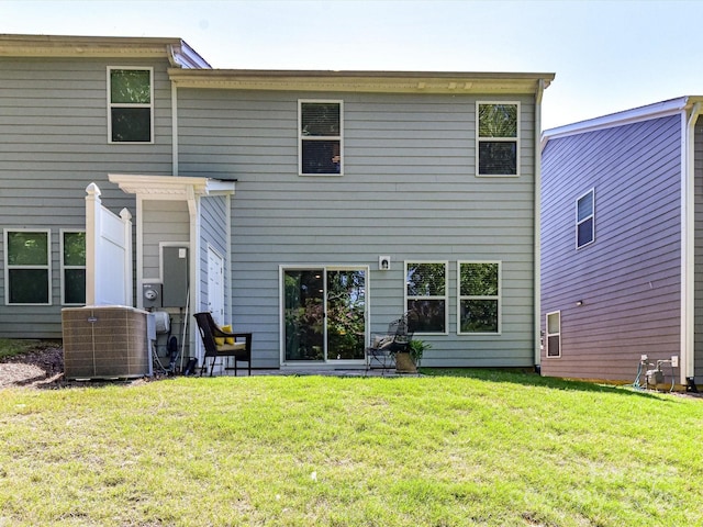 rear view of property featuring central AC and a lawn
