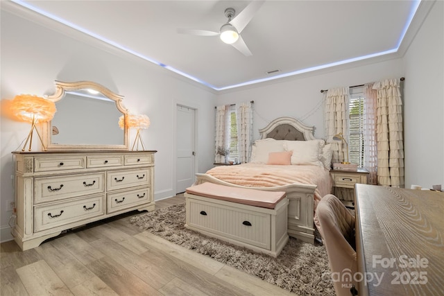 bedroom with light wood finished floors, visible vents, crown molding, and ceiling fan