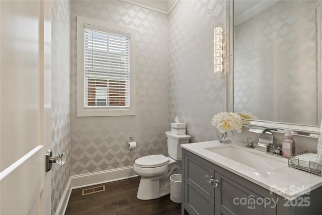 bathroom with vanity, crown molding, toilet, visible vents, and wood finished floors