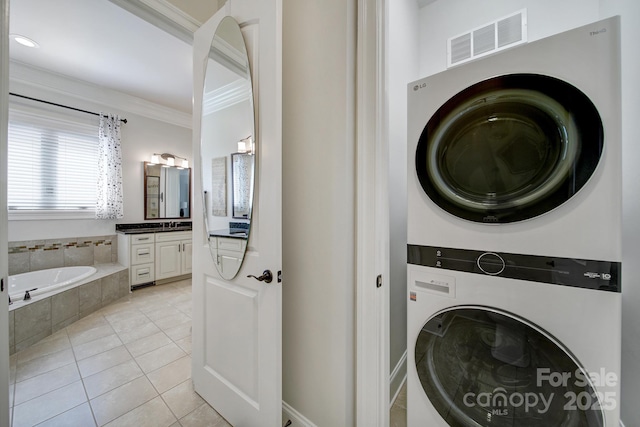 141 Forsythia Ln, Tega Cay, SC 29708 - laundry room with visible vents, light tile patterned floors, ornamental molding, stacked washer / dryer, and laundry area