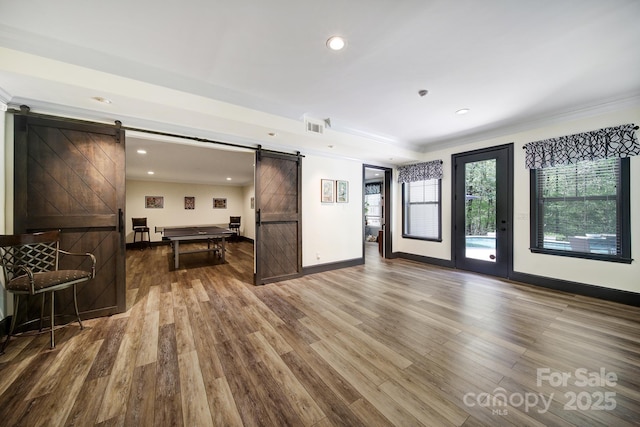 141 Forsythia Ln, Tega Cay, SC 29708 - unfurnished living room with baseboards, ornamental molding, a barn door, visible vents, and wood finished floors