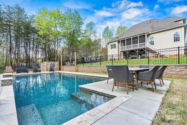view of pool with a patio, a fenced backyard, a shed, a sunroom, and an outbuilding